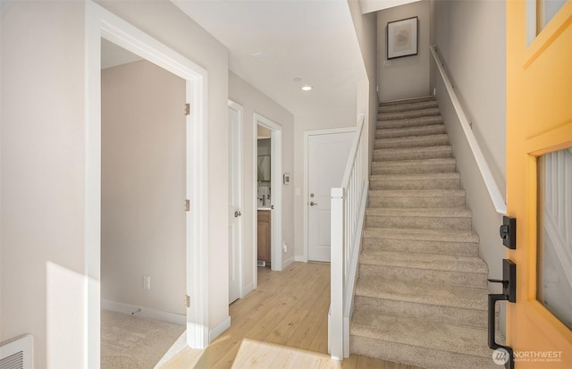 stairway featuring wood finished floors, recessed lighting, and baseboards