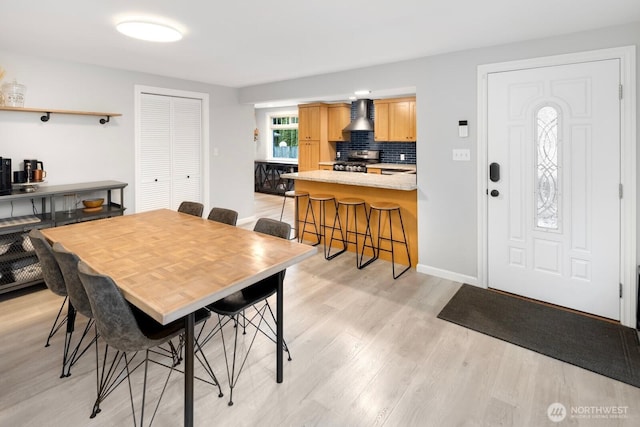 dining space featuring light wood finished floors and baseboards