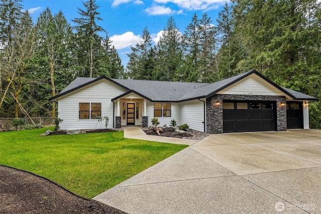 view of front facade featuring a front lawn, stone siding, fence, concrete driveway, and a garage