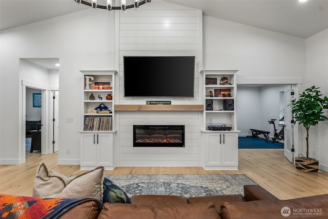 living area featuring baseboards, a fireplace, high vaulted ceiling, and light wood-style floors