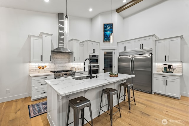 kitchen with high quality appliances, high vaulted ceiling, a sink, a kitchen breakfast bar, and wall chimney exhaust hood