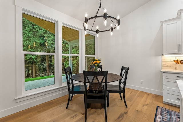 dining space with a chandelier, baseboards, and light wood-style flooring