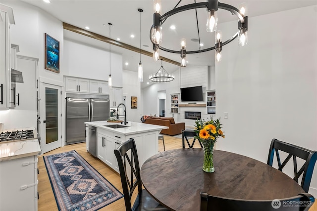 dining space featuring recessed lighting, light wood-type flooring, a large fireplace, and a towering ceiling