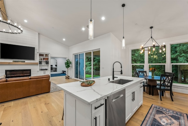 kitchen featuring dishwasher, a glass covered fireplace, light wood-style flooring, and a sink