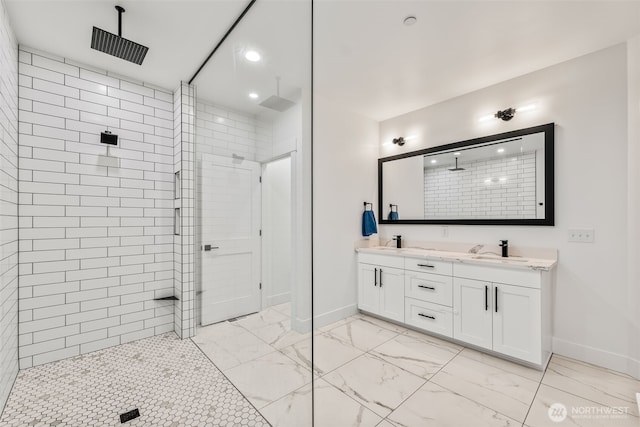 full bathroom with double vanity, marble finish floor, tiled shower, and a sink