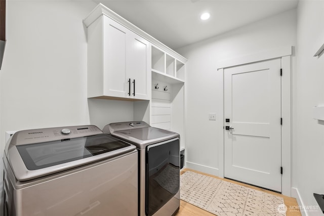 clothes washing area with washer and clothes dryer, recessed lighting, cabinet space, light wood-style floors, and baseboards