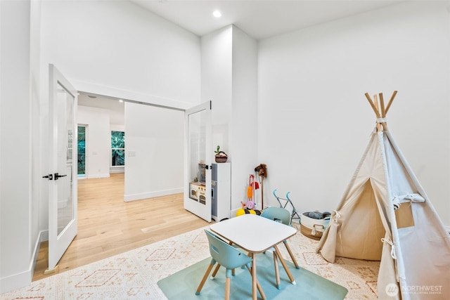 game room featuring recessed lighting, baseboards, a high ceiling, and light wood finished floors