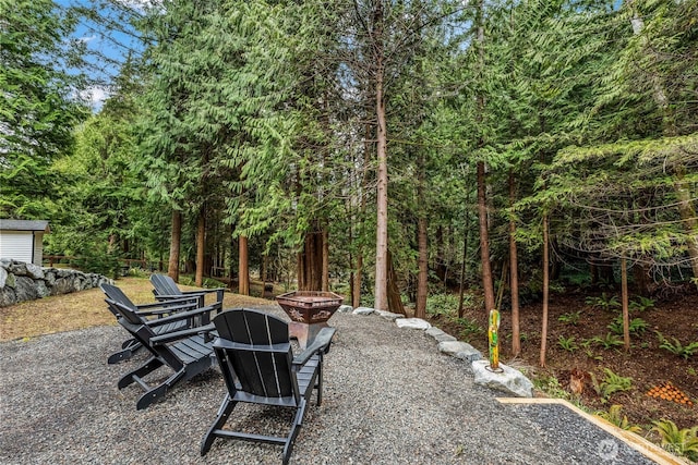 view of patio with a wooded view and an outdoor fire pit