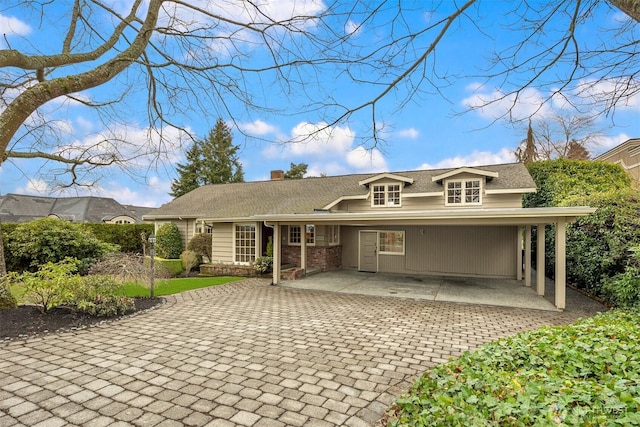 view of front of home with a carport, a chimney, and decorative driveway