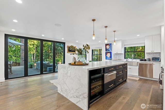 kitchen featuring dishwasher, a warming drawer, tasteful backsplash, and white cabinetry