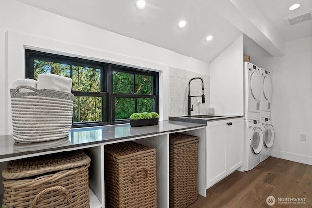 laundry room with recessed lighting, cabinet space, dark wood-style flooring, a sink, and stacked washer and clothes dryer