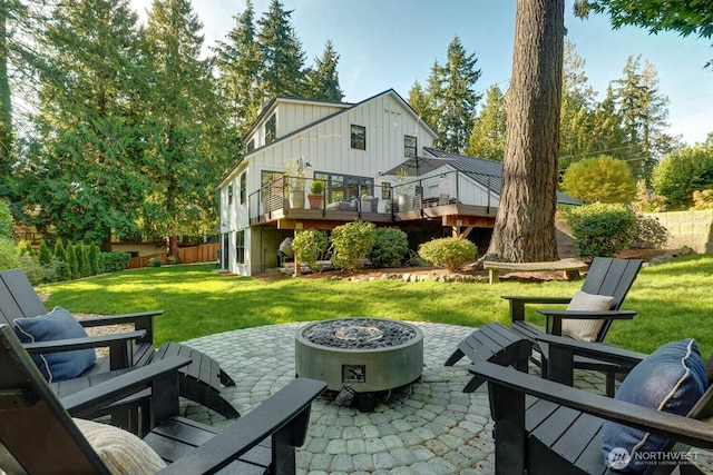 back of house featuring a yard, board and batten siding, a fire pit, and a patio