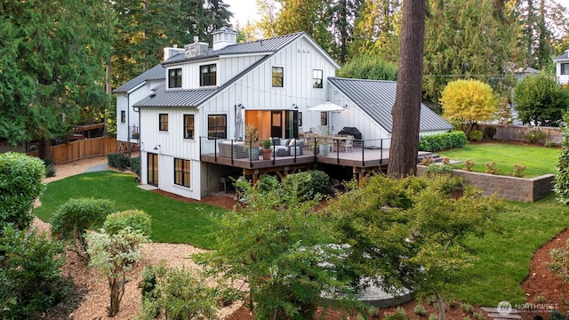 rear view of house featuring a lawn, metal roof, a fenced backyard, a deck, and a standing seam roof