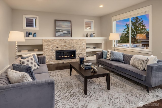 living area featuring a stone fireplace, recessed lighting, and wood finished floors