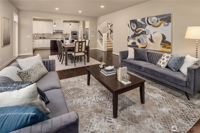 living room with dark wood-type flooring, baseboards, stairway, recessed lighting, and arched walkways