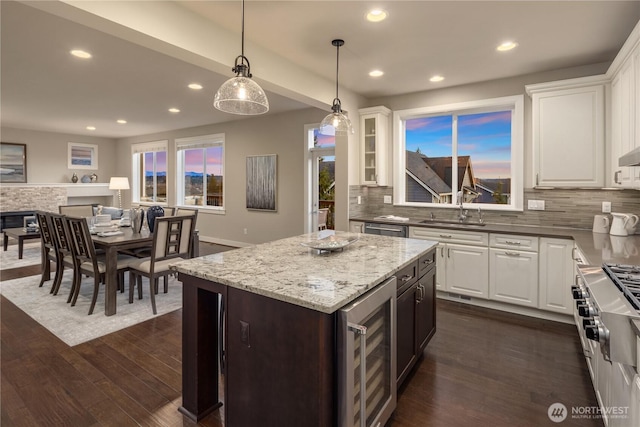 kitchen with beverage cooler, white cabinetry, and a sink