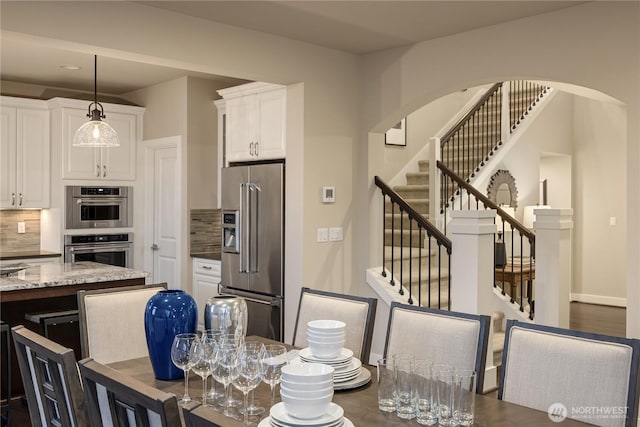 dining space featuring stairs, baseboards, and arched walkways