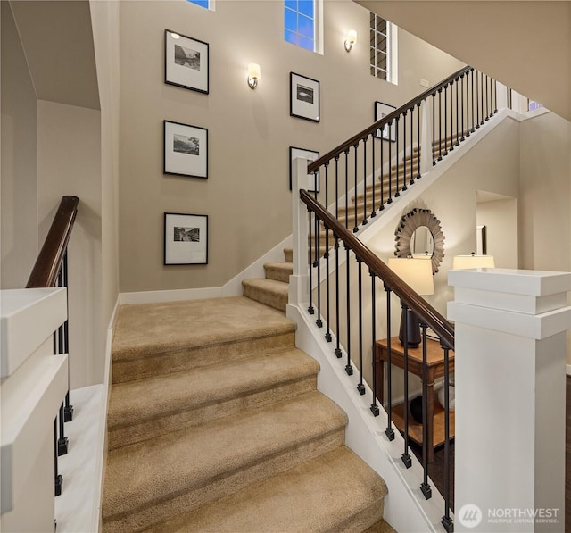 staircase with baseboards and a high ceiling