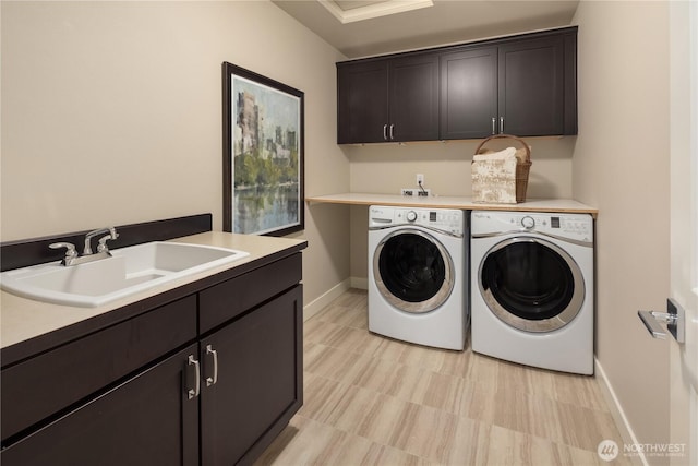 clothes washing area with separate washer and dryer, cabinet space, baseboards, and a sink