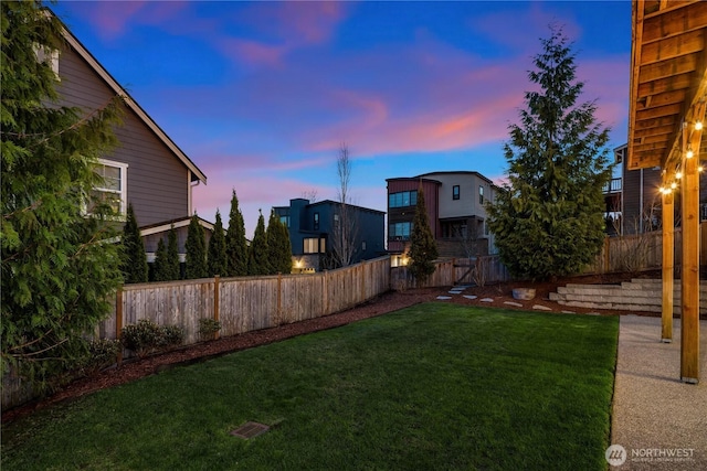 yard at dusk featuring a fenced backyard