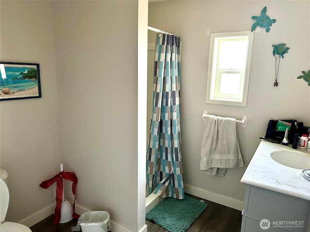 bathroom featuring toilet, vanity, baseboards, and wood finished floors