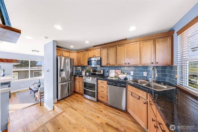 kitchen featuring tasteful backsplash, baseboards, light wood-style floors, stainless steel appliances, and a sink