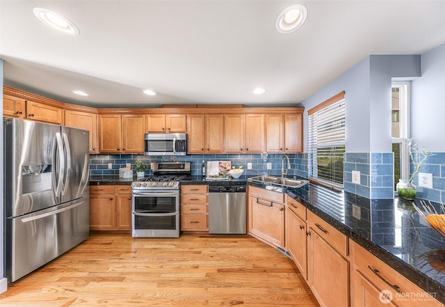 kitchen with light wood-type flooring, recessed lighting, a sink, stainless steel appliances, and tasteful backsplash