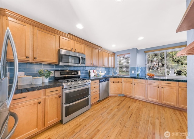 kitchen with a sink, recessed lighting, light wood-style floors, appliances with stainless steel finishes, and decorative backsplash