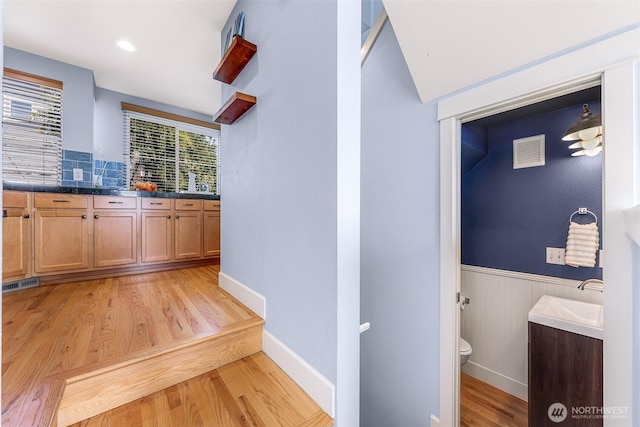 interior space featuring a wainscoted wall, visible vents, light wood-style floors, and a sink