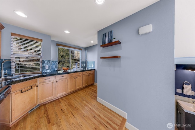 kitchen with baseboards, a sink, decorative backsplash, dishwasher, and light wood-type flooring