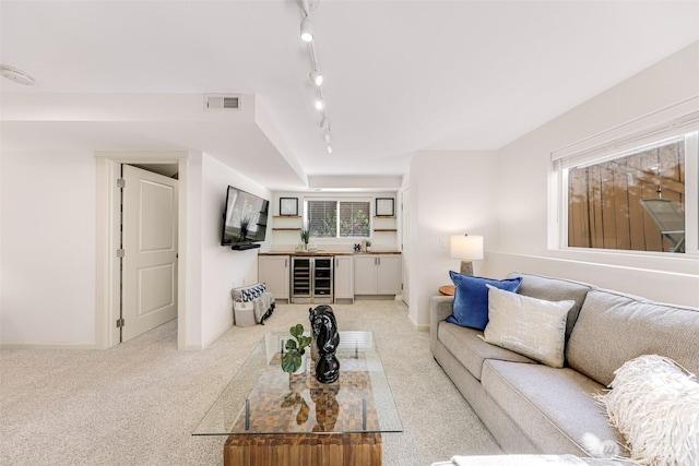 living room featuring wine cooler, light colored carpet, visible vents, and a wealth of natural light