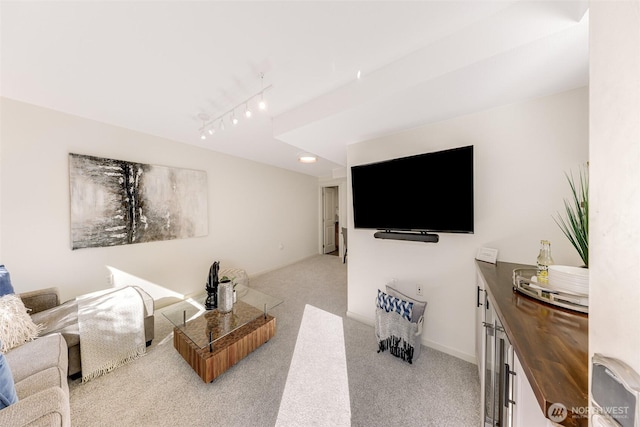 living room featuring track lighting, light colored carpet, and baseboards