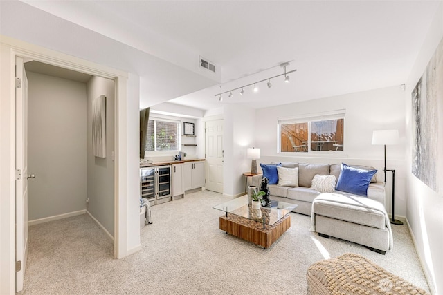 living room featuring wine cooler, visible vents, light carpet, and baseboards