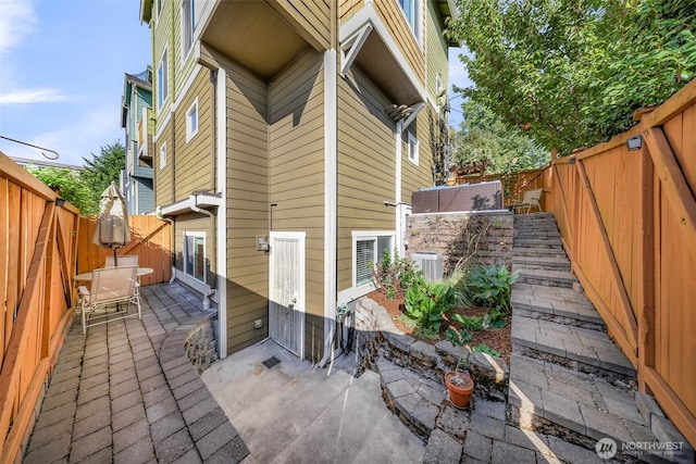 view of side of home featuring a patio, central AC unit, and a fenced backyard