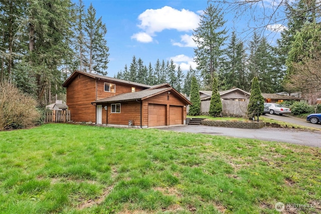 view of front of property featuring a front yard, fence, a garage, and driveway