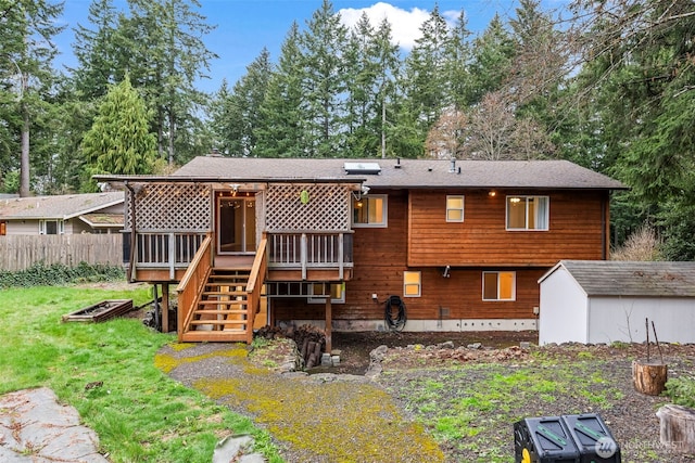 rear view of property featuring an outbuilding, fence, a wooden deck, a yard, and a storage shed