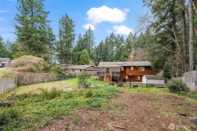 view of yard with a deck, an outbuilding, a fenced backyard, and a storage shed