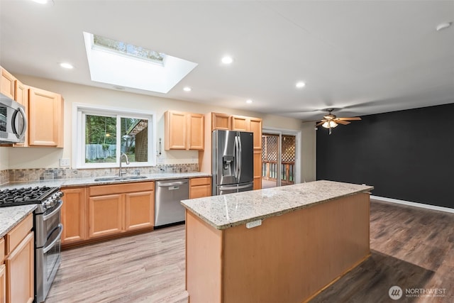 kitchen featuring a sink, light brown cabinets, light wood-style floors, and stainless steel appliances