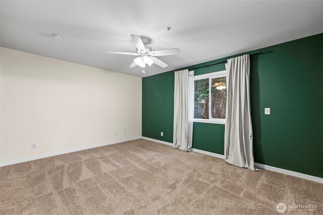 carpeted spare room with a ceiling fan and baseboards