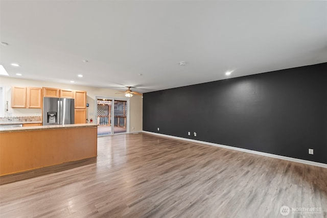 unfurnished living room featuring an accent wall, ceiling fan, baseboards, light wood-type flooring, and recessed lighting