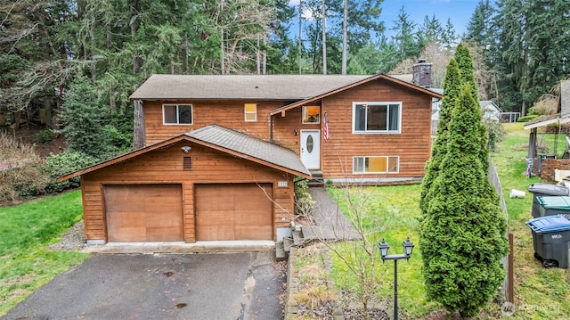 split foyer home featuring aphalt driveway, a front lawn, a garage, and a chimney