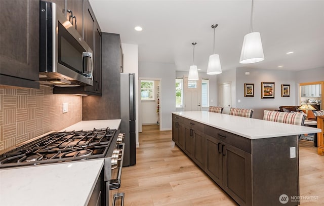 30 Sundae Dr, Sequim, WA 98382 - kitchen featuring dark brown cabinetry, light wood finished floors, backsplash, and stainless steel appliances