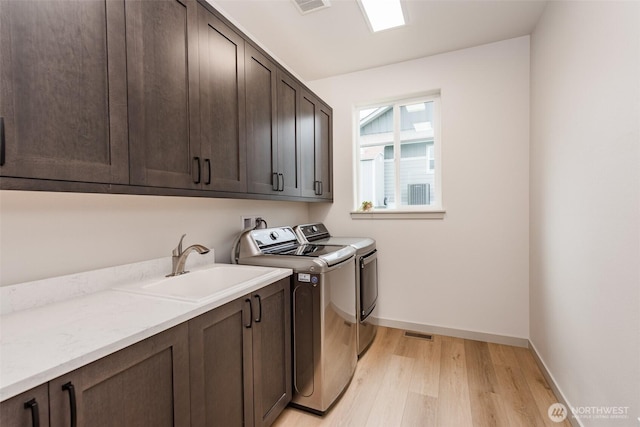 30 Sundae Dr, Sequim, WA 98382 - laundry area with light wood finished floors, baseboards, washer and dryer, cabinet space, and a sink