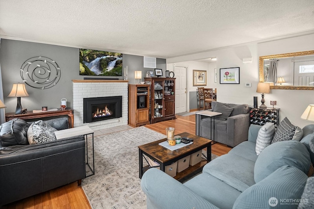 living room with a textured ceiling, a brick fireplace, and wood finished floors