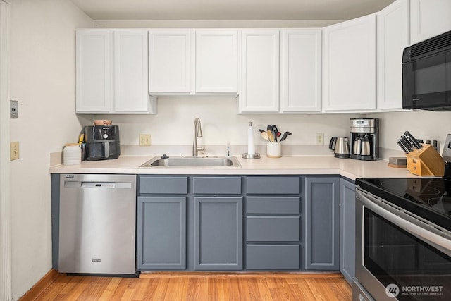 kitchen with gray cabinets, stainless steel appliances, light countertops, and a sink