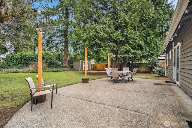 view of patio featuring a shed, outdoor dining space, an outdoor structure, and a fenced backyard