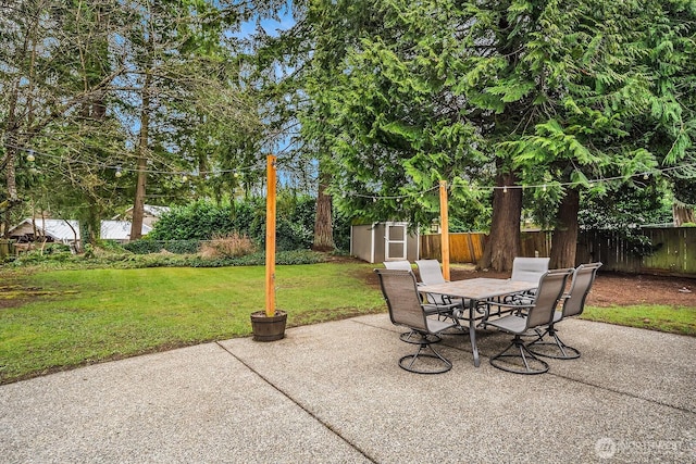 view of patio / terrace featuring an outbuilding, a storage shed, a fenced backyard, and outdoor dining space