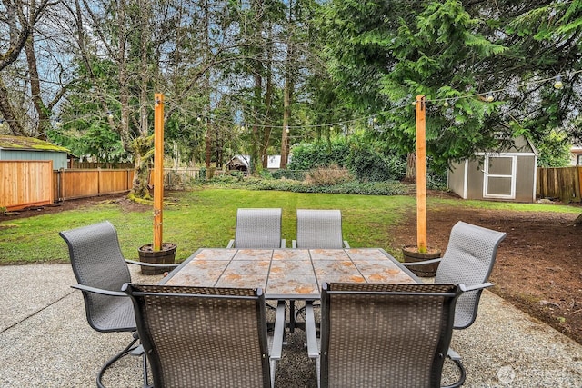 view of patio with outdoor dining space, an outdoor structure, a fenced backyard, and a shed