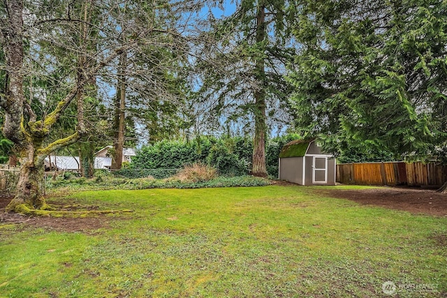 view of yard with an outbuilding, a storage shed, and fence