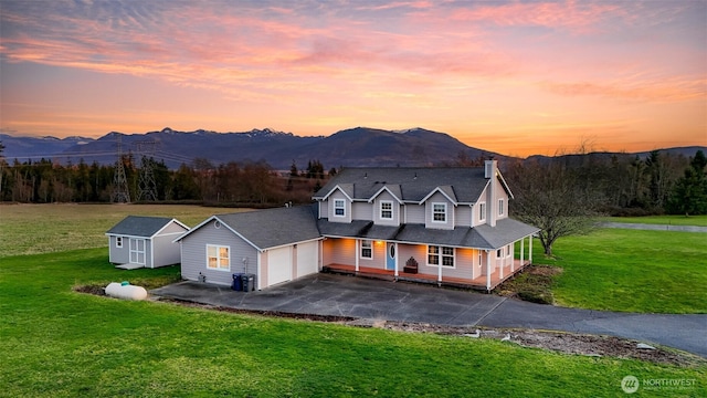 view of front of property featuring a mountain view, a yard, covered porch, and driveway